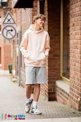 Adolescent portant un hoodie oversize rose pâle et un short gris, un look streetwear Happy Kid'z by Nancy.